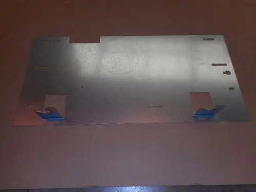 Metallplatte mit Ausschnitten und Löchern, möglicherweise für eine Montageanwendung, sichtbar in einer Werkstatt oder auf einem Tisch. Marke: Remeha.